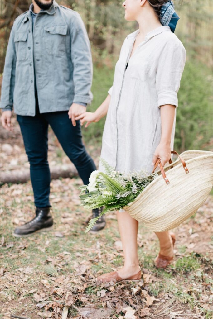 Couple holding hands while foraging for greenery for their destination wedding decor
