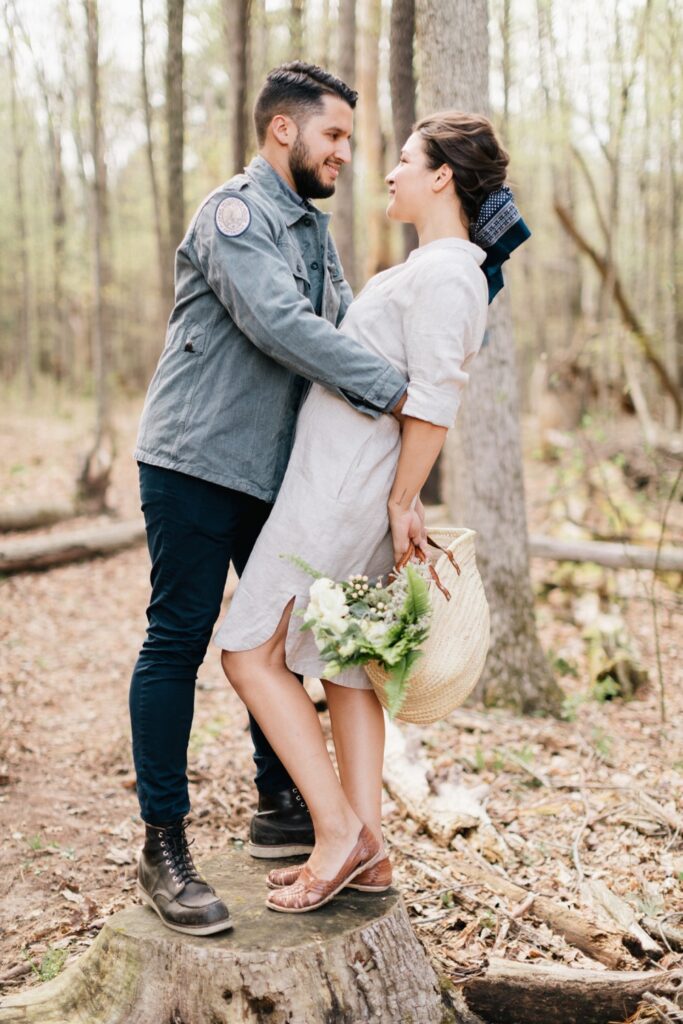 Couple cuddling while foraging for their wedding greenery before a rustic destination wedding in upstate New York