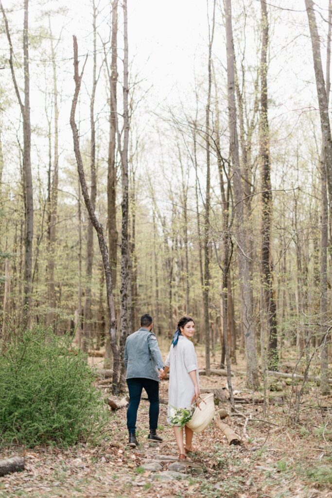 Bride and groom holding hands while foraging for their wedding flowers at an intimate destination wedding at Foxfire Mountain House