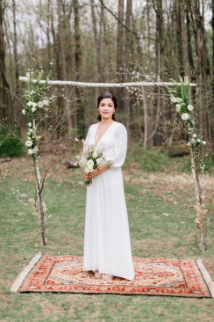 Bride in front of a rustic ceremony arch at an intimate destination wedding in New York