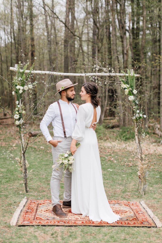 Bride and groom in front of a rustic ceremony arch at an intimate outdoor ceremony at Foxfire Mountain House