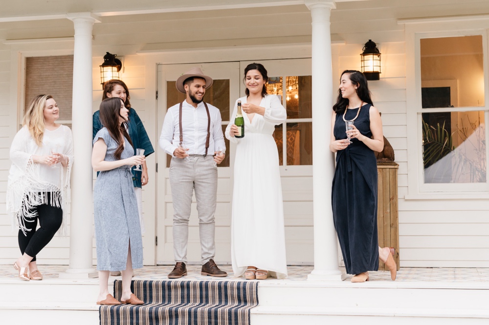 Bride popping champagne after a rustic and intimate outdoor wedding ceremony by Emily Wren Photography