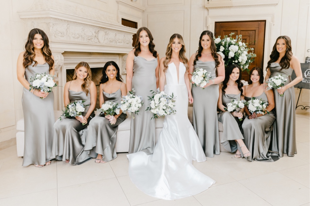 Bride and bridesmaids in grey dresses smiling on a rainy spring wedding day in New Jersey