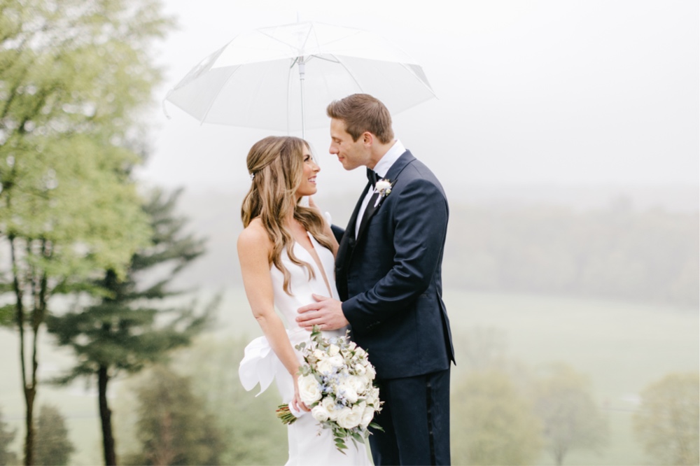 Bride and groom smiling on a romantically rainy wedding day by Emily Wren Photography