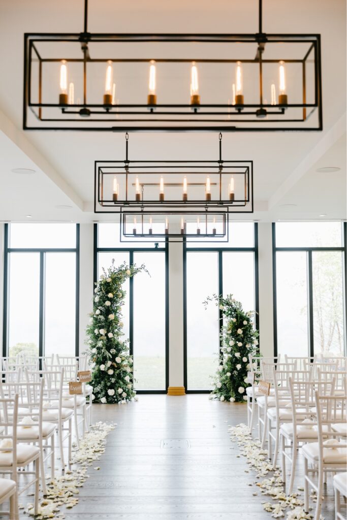 Indoor wedding ceremony at Natirar with white flowers and a dramatic ceremony arch