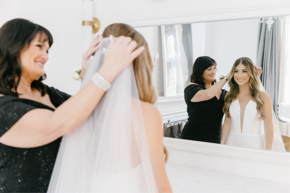 Mother of the bride helping with the veil before an intimate indoor wedding ceremony