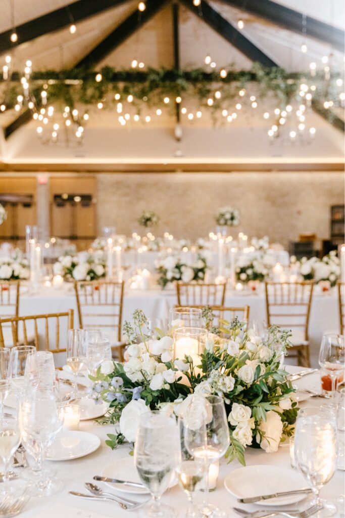 Low white flower arrangements with blue accents for an elegant spring wedding reception