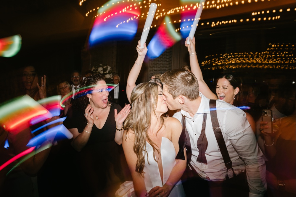Newlyweds kiss on the dance floor during an energetic wedding reception