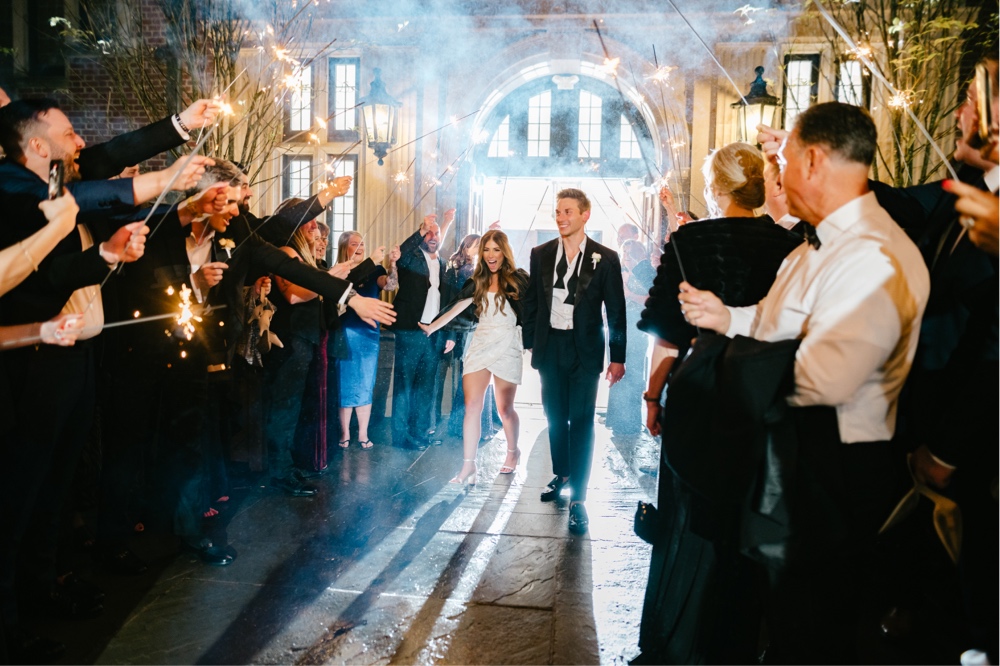 Bride and groom laughing during an exciting sparkler exit by Emily Wren Photography