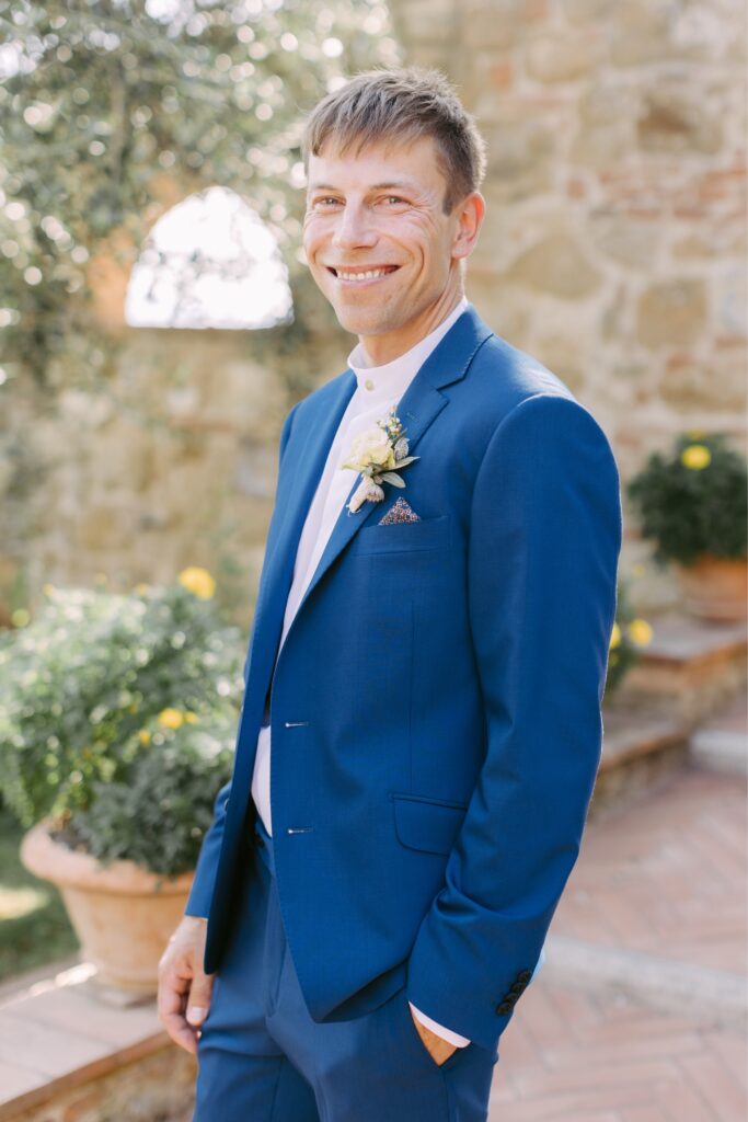 Groom in a blue suit smiling before his wedding ceremony in Italy by Emily Wren Photography