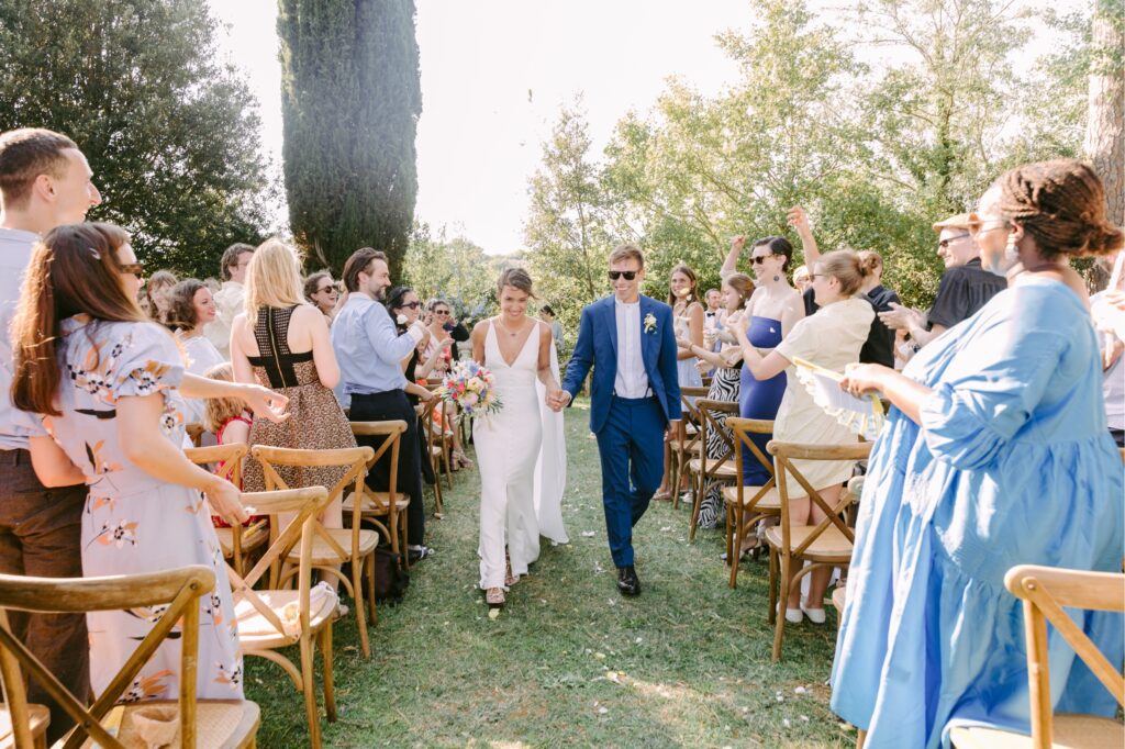 Wedding guests throwing flower petals as the newlyweds walk down the aisle by Emily Wren Photography