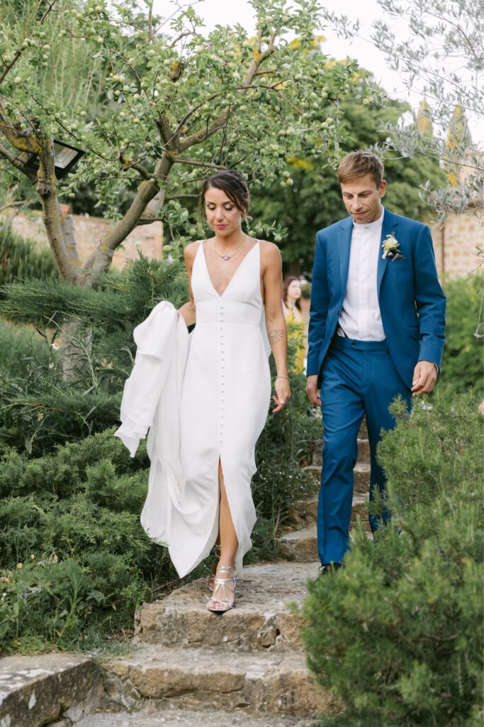 Bride and groom walking down stone steps at the Borgo estate in Tuscany by Emily Wren Photography