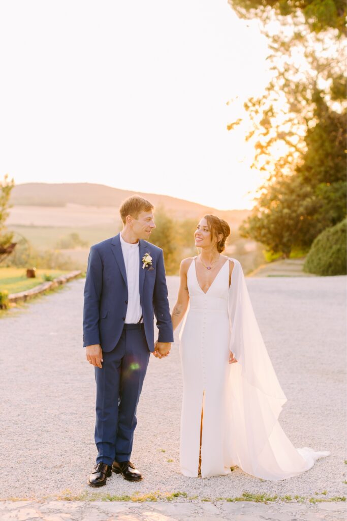 Newlyweds holding hands at sunset at a destination wedding in Tuscany by Emily Wren Photography