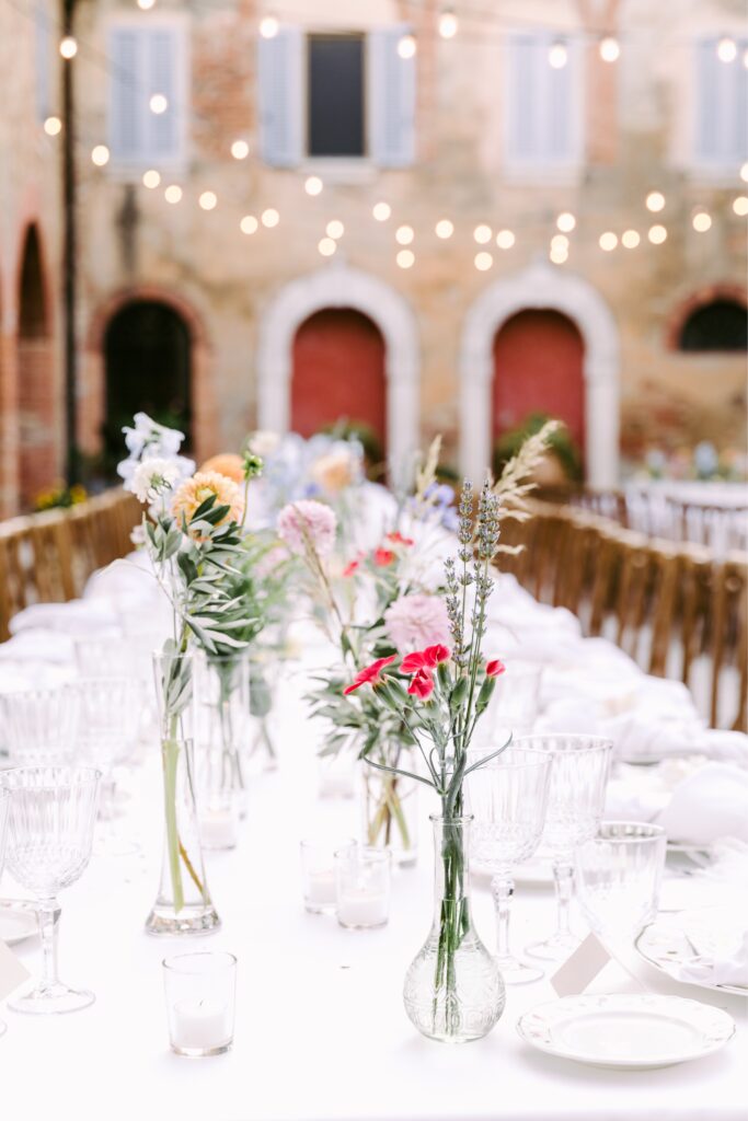 Wildflowers in bud vases under twinkle lights at a historic estate in Tuscany by Emily Wren Photography