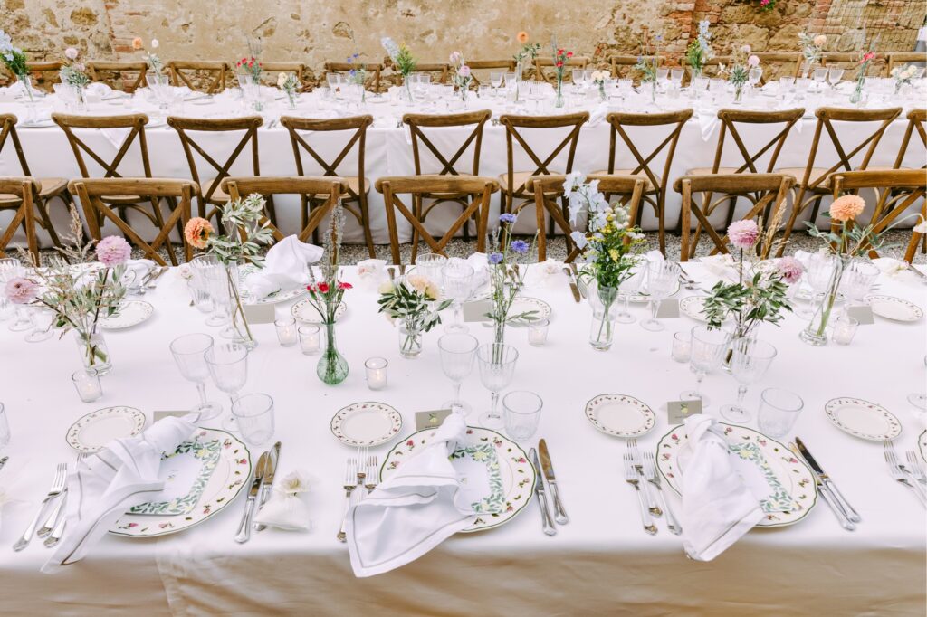 Long wedding reception tables with bud vases filled with wildflowers