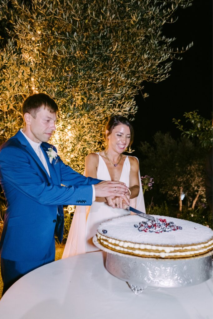 Newlyweds cut their wedding cake at an enchanting destination wedding in Tuscany by Emily Wren Photography
