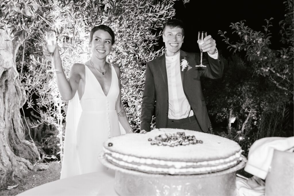 Bride and groom drink champagne at their al fresco wedding reception in Tuscany