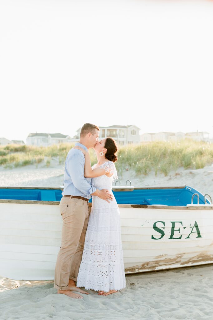 Couple kissing in front of boats on the beach at the Jersey Shore
