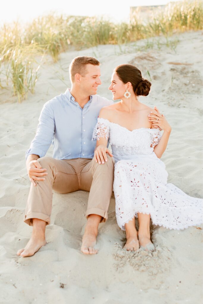 Couple sitting in the sand dunes at the New Jersey Shore by Emily Wren Photography