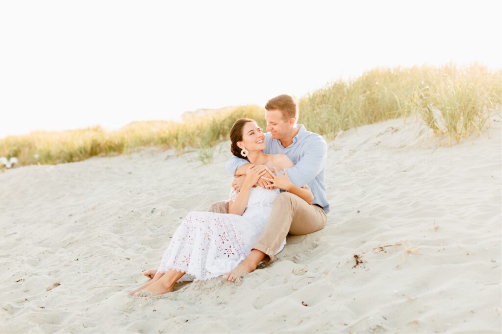 Couple sitting in the sand dunes for a sunset beach engagement shoot in NJ