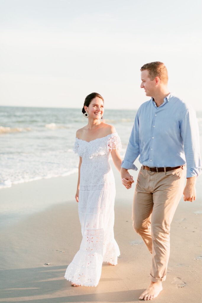 Couple walking by the ocean in Sea Isle, New Jersey during an engagement shoot with Emily Wren Photography