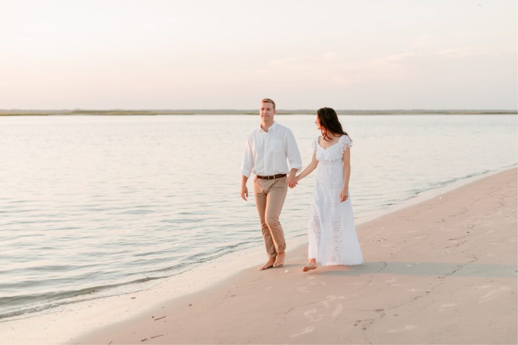 Couple holding hands and walking by the ocean at sunset by Emily Wren Photography