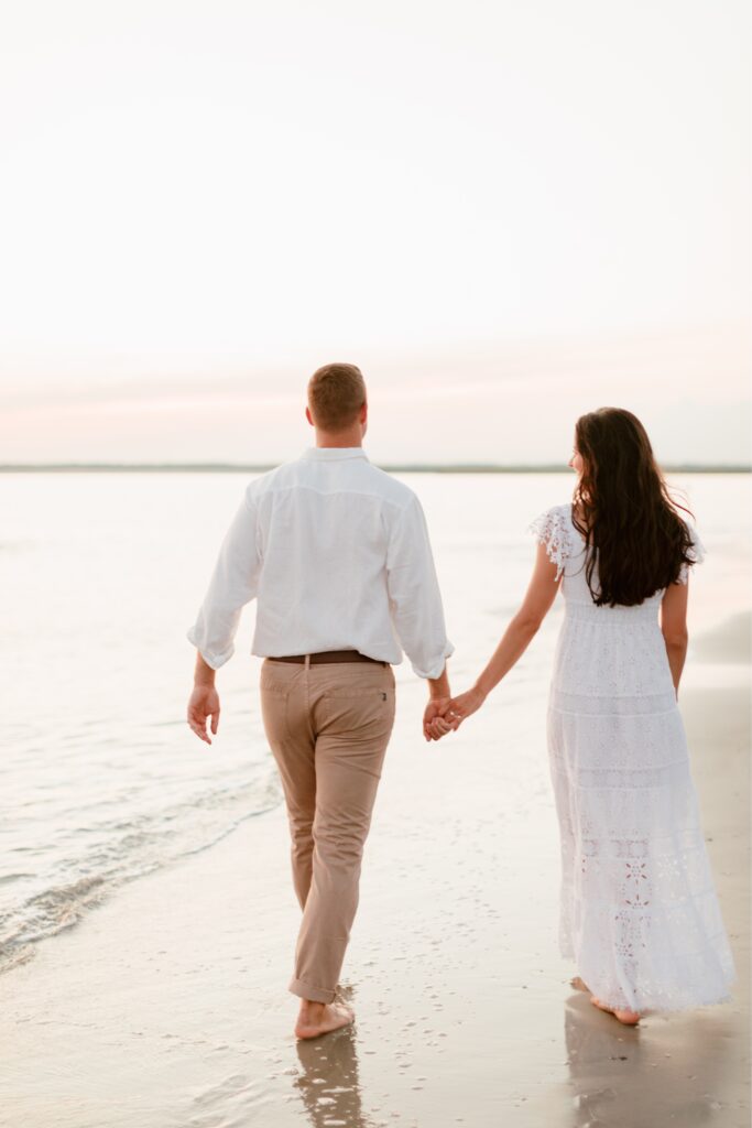 Couple walking towards the sunset during a romantic beach engagement shoot by Emily Wren Photography