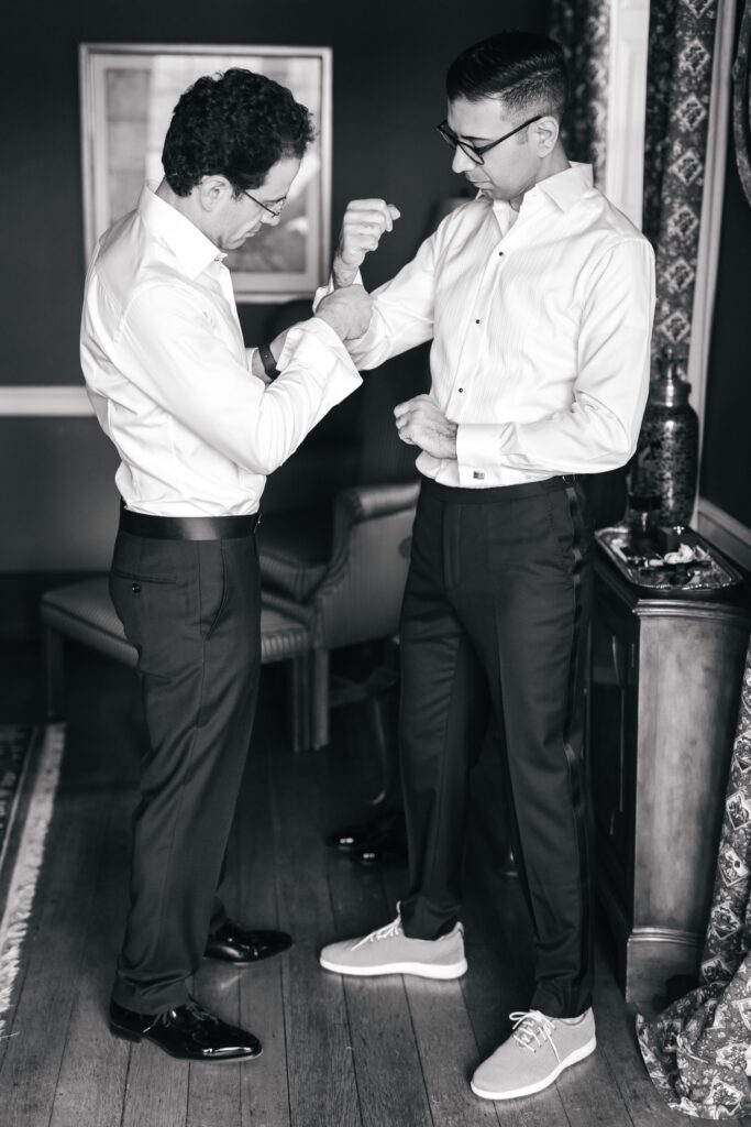 a groom getting ready with help from a groomsman for his spring wedding