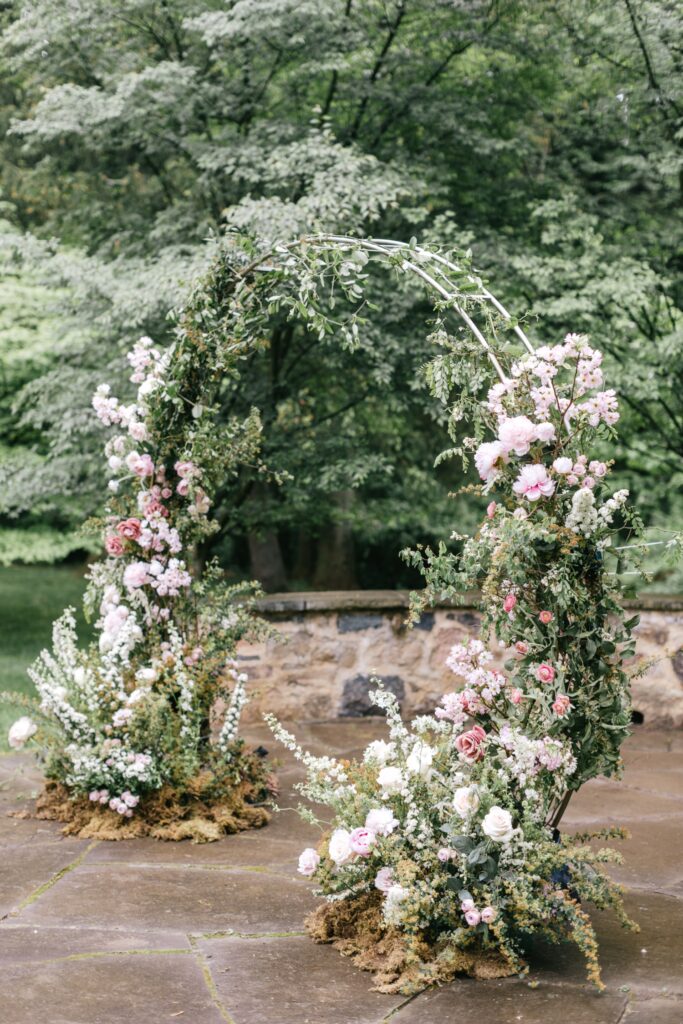 floral wedding arch consisting of Spring blush pink, coral, and babies breath flowers