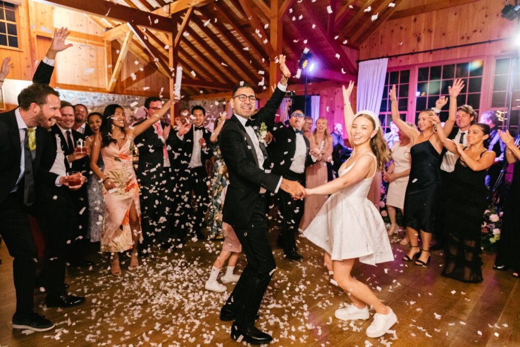 bride and groom dancing at the end of their wedding reception as guests throw flower petals on them