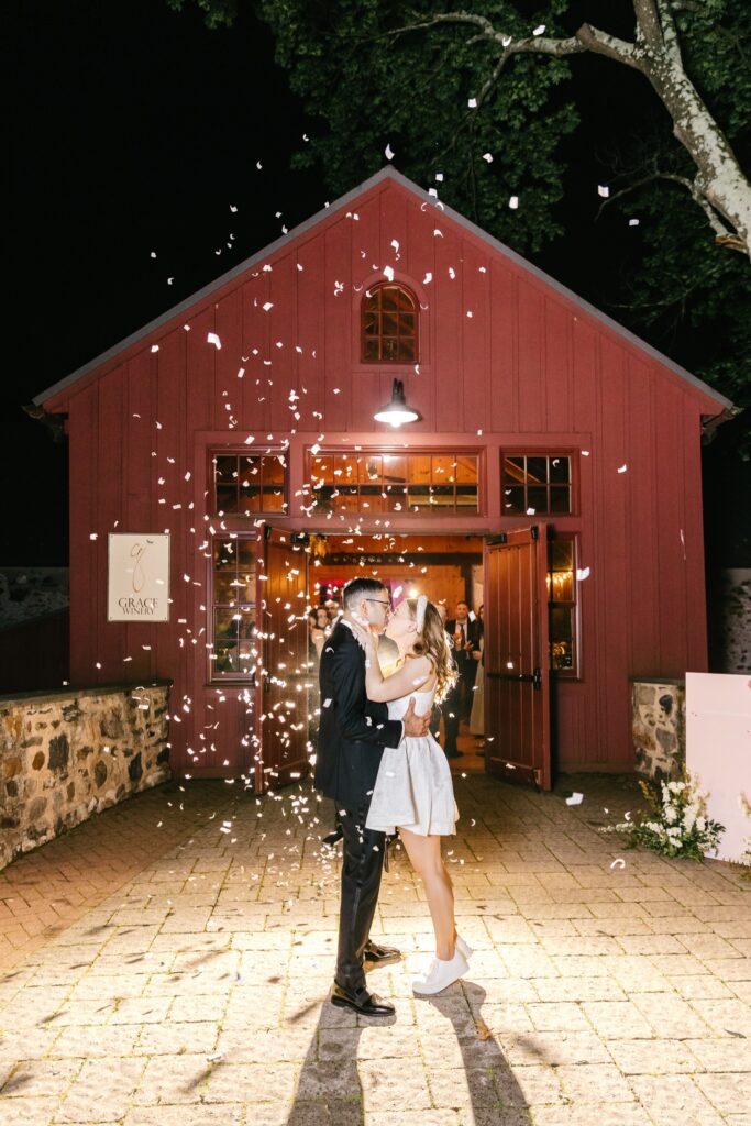 bride and groom kissing as flower petals fly around them