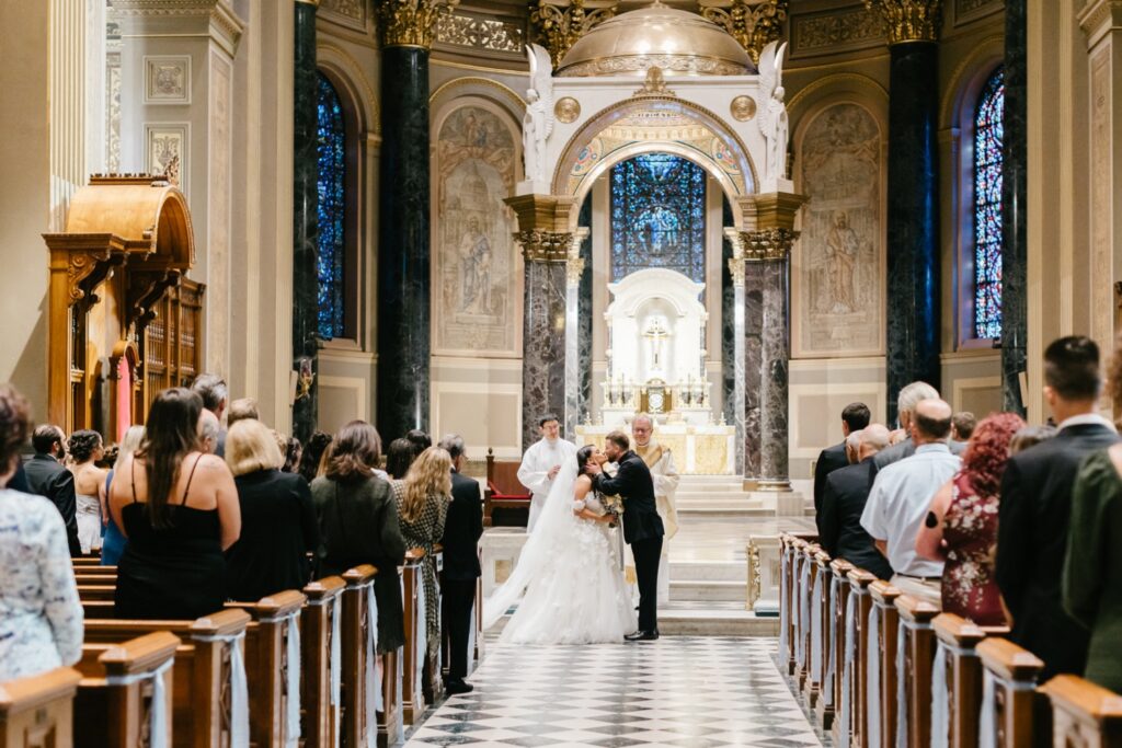 bride and grooms first kiss during their catholic wedding ceremony