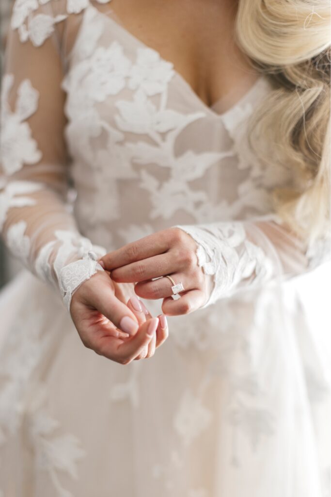 Bride adjusting floral lace sleeves of her wedding dress