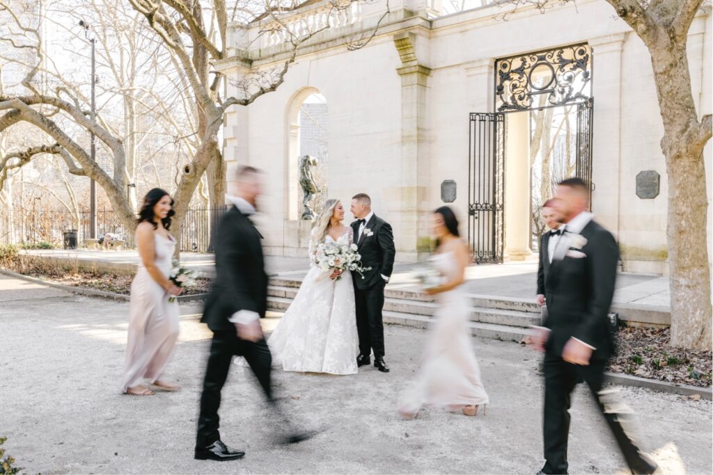slow motion photo of bridal party as the bride and groom stand still by Emily Wren Photography