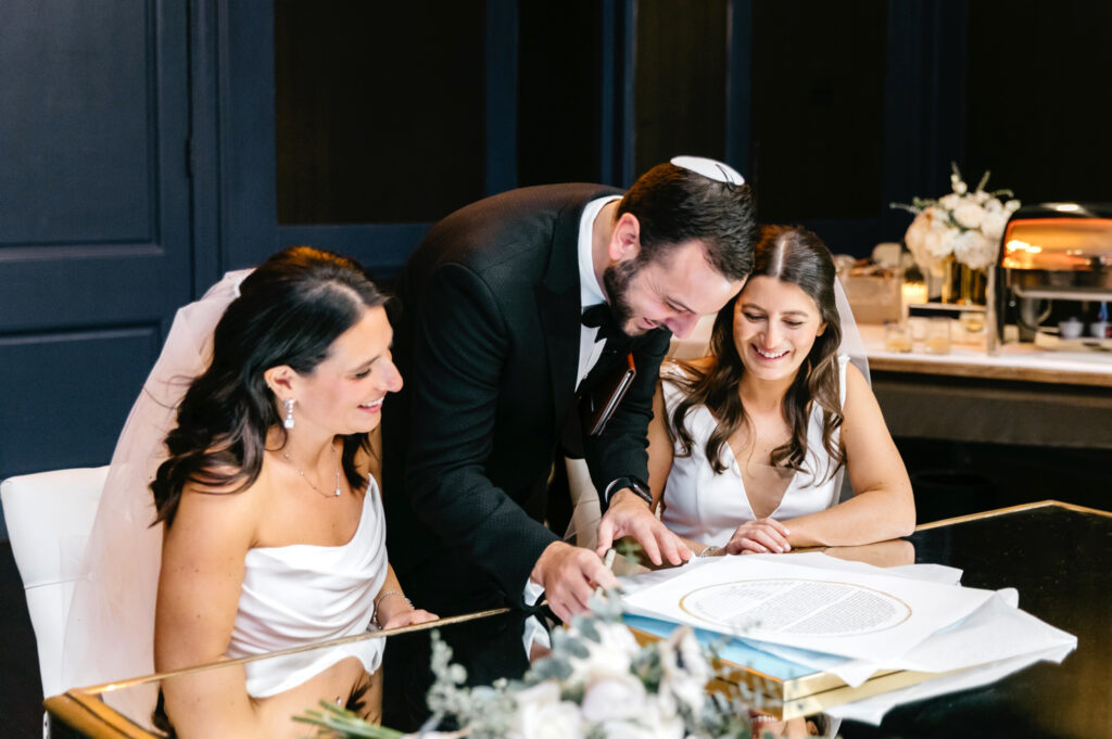 lesbian couple signing ketubah for Philadelphia wedding ceremony