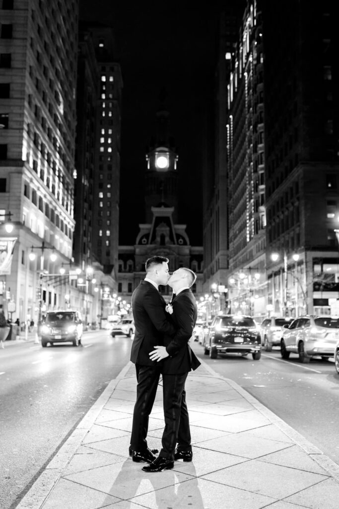 gay couple kissing in front of City Hall after their Philadelphia wedding reception by Emily Wren Photography