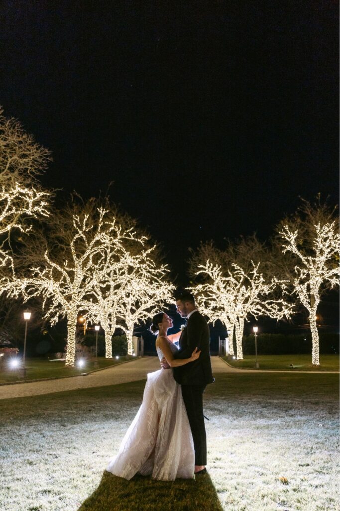 bride and groom portrait in front of lit up trees in New Jersey by Emily Wren Photography