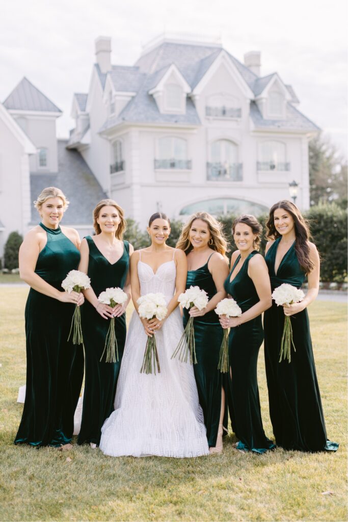 bride with her bridesmaids in green velvet dresses outside of Park Chateau for her winter wedding