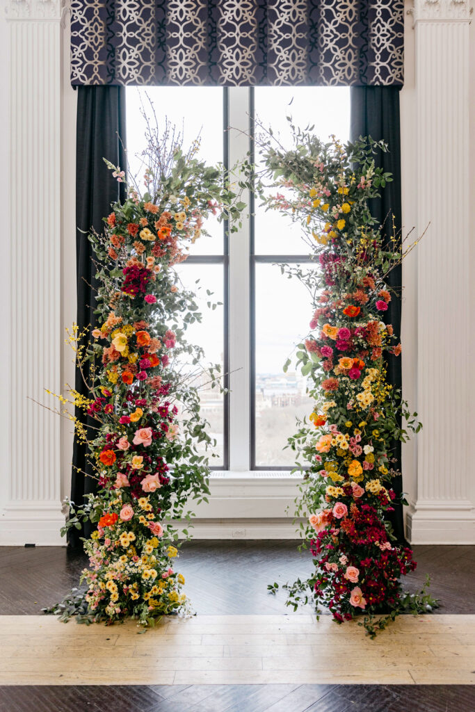 Floral arch for a wedding ceremony with Vibrant colorful spring flowers by Emily Wren Photography