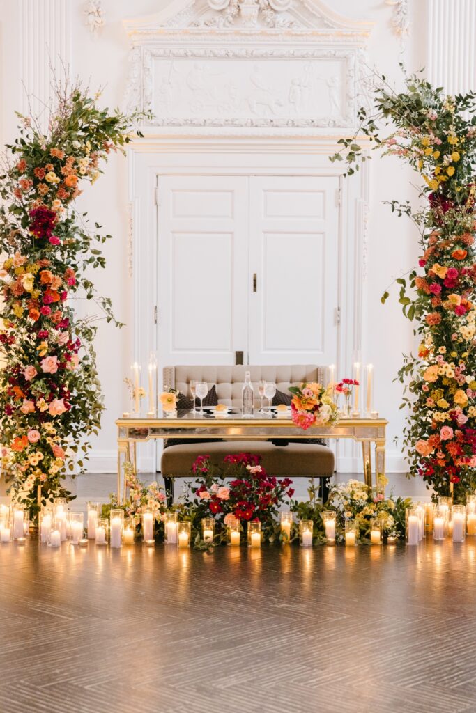 sweetheart table at a Philadelphia spring wedding reception with colorful pink orange and yellow flowers and candlelight