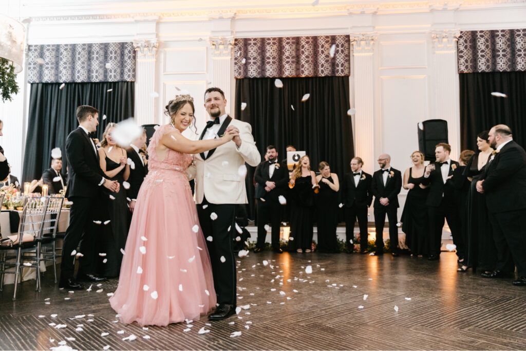 bride and grooms first dance at the downtown club as they're showered with pink flower petals