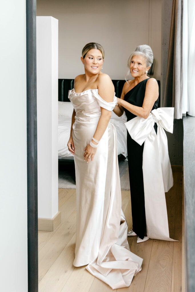 bride getting into her wedding dress as her mother helps her