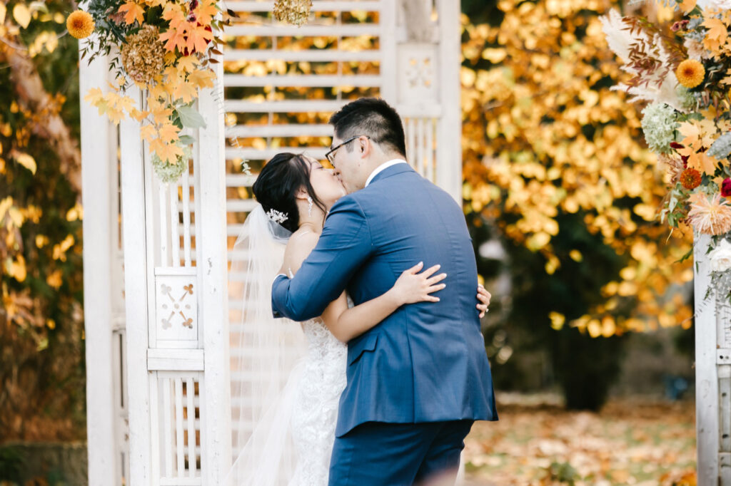 bride & grooms first kiss during Fall wedding ceremony in Glen Mills Pennsylvania