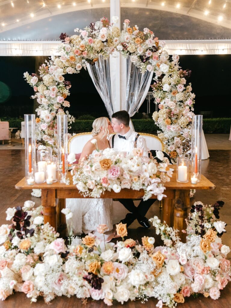 Bride & grooms sweetheart table at Philadelphia summer wedding ceremony with white, burgundy, burnt orange, & pink flowers