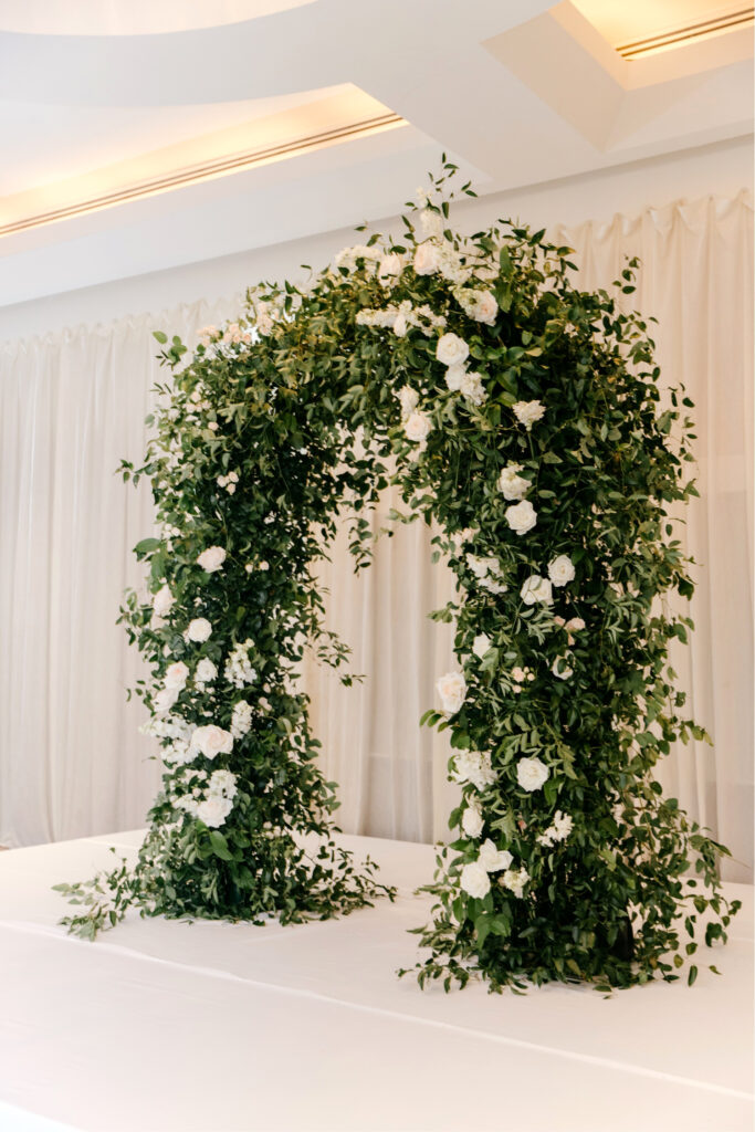 white floral and lush greenery floral arch for wedding ceremony