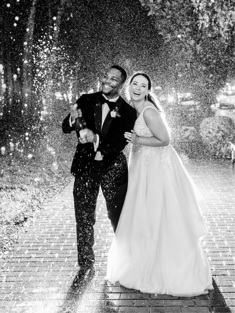 bride & groom pop champagne after their Washington DC wedding reception day by Emily Wren Photography