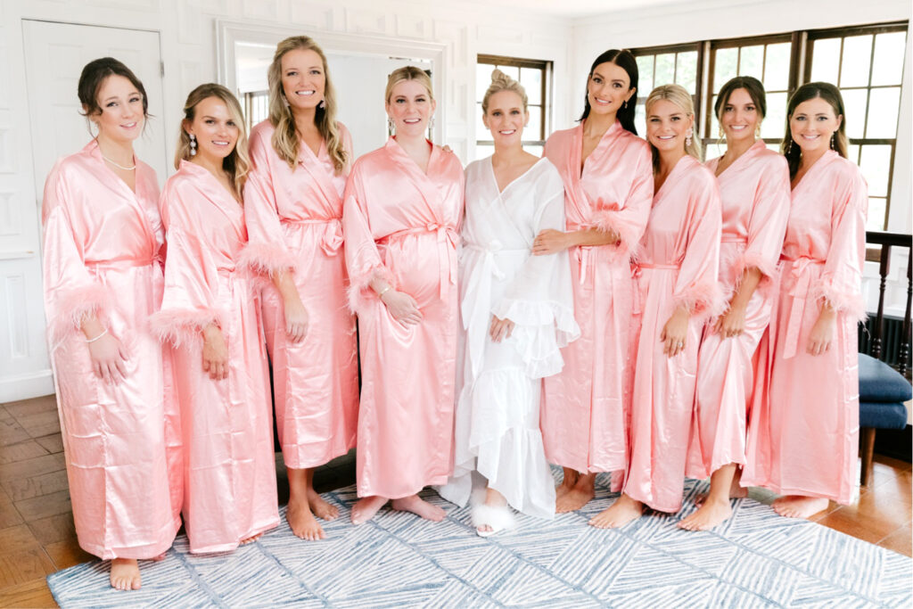 bride with her bridesmaids in pink satin robes before her wedding day