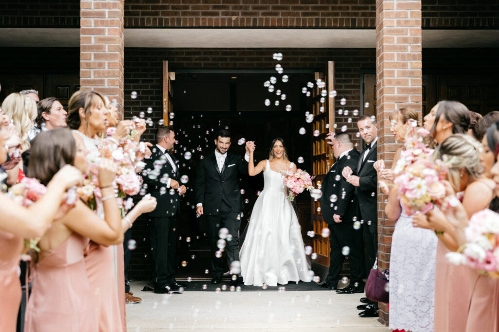 bride & groom exiting church wedding ceremony as guests blow bubbles