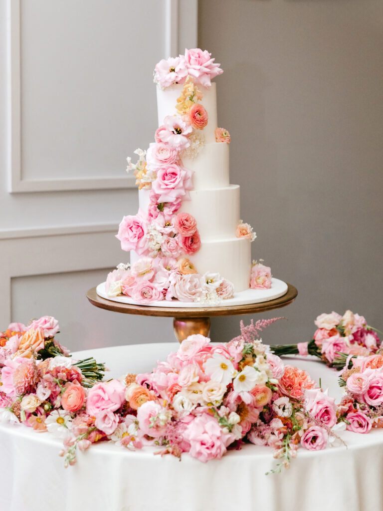 4 tier wedding cake decorate with various pink flowers