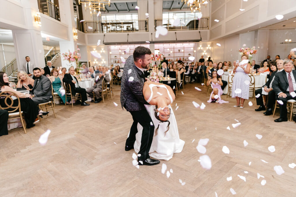 bride & grooms first dance as guests throw pink flower petals on them